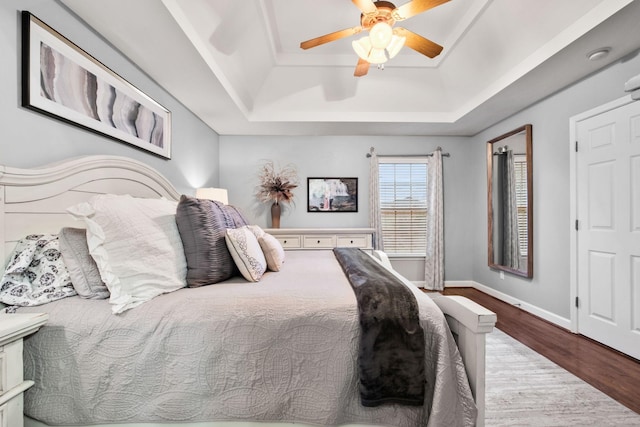 bedroom featuring a raised ceiling, ceiling fan, and hardwood / wood-style floors