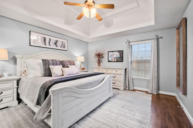 bedroom with a tray ceiling, ceiling fan, and hardwood / wood-style floors