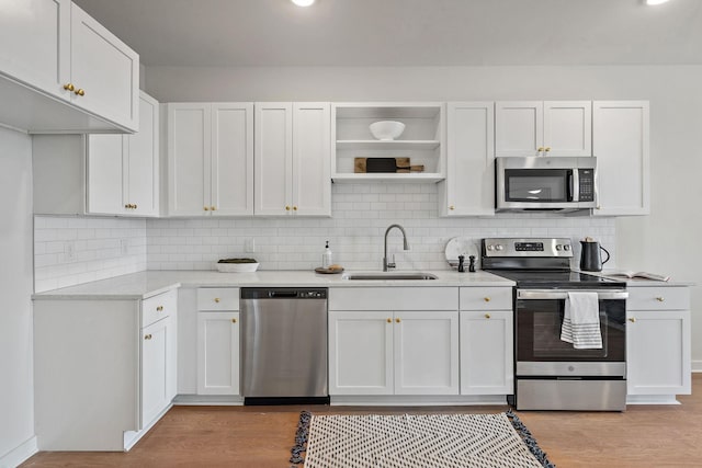 kitchen featuring white cabinets, appliances with stainless steel finishes, light hardwood / wood-style flooring, and sink