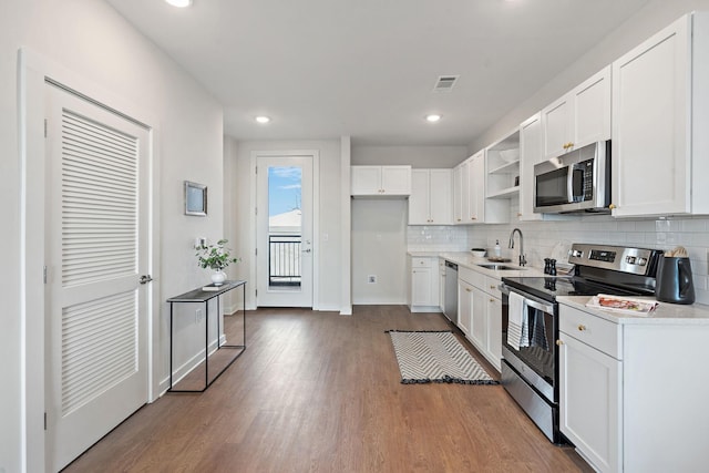 kitchen with hardwood / wood-style floors, backsplash, sink, appliances with stainless steel finishes, and white cabinetry