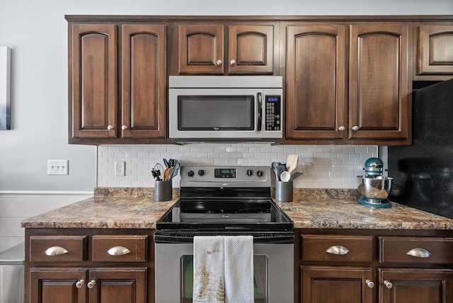 kitchen with dark brown cabinetry, light stone counters, stainless steel appliances, and decorative backsplash