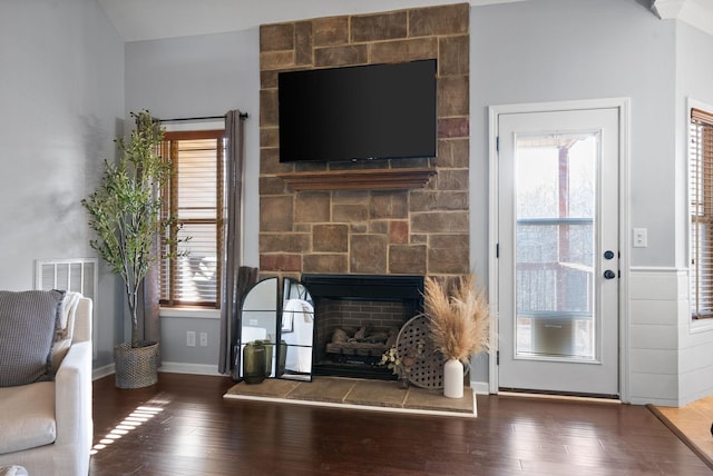 living room with a large fireplace and dark wood-type flooring