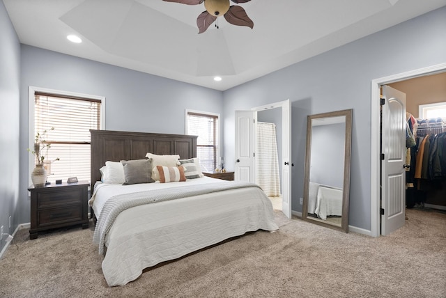 bedroom featuring a walk in closet, light carpet, a closet, and ceiling fan