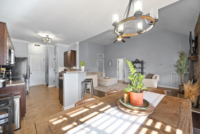 tiled dining space with ceiling fan, vaulted ceiling, and ornamental molding