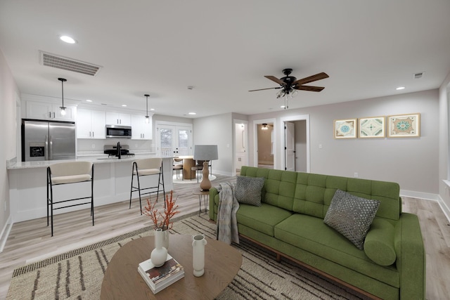 living room featuring ceiling fan, sink, and light hardwood / wood-style flooring