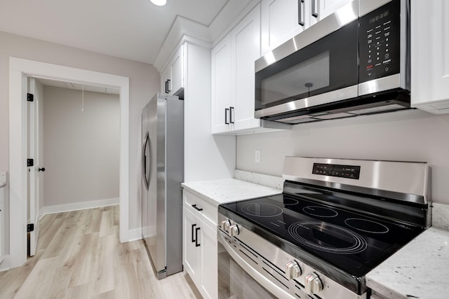 kitchen with light stone counters, light hardwood / wood-style flooring, white cabinets, and appliances with stainless steel finishes