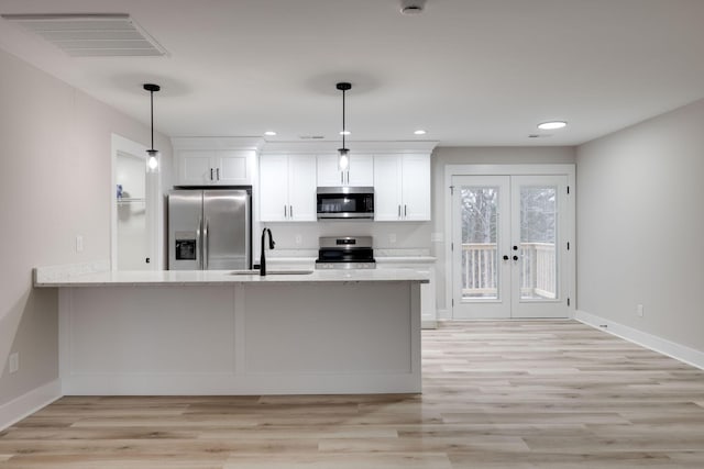 kitchen featuring light stone countertops, appliances with stainless steel finishes, sink, white cabinets, and hanging light fixtures