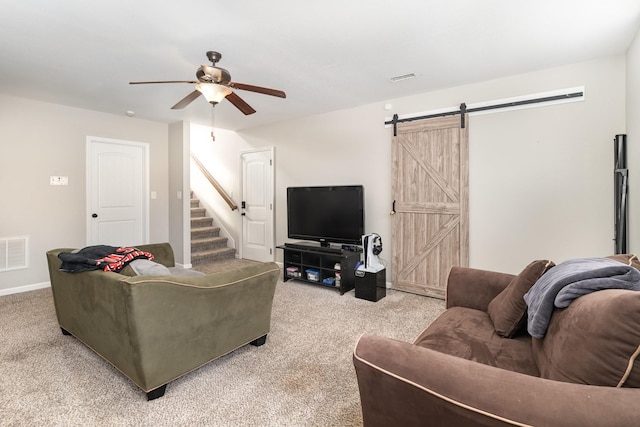 living room featuring ceiling fan, a barn door, and light colored carpet