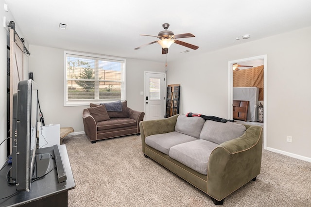 carpeted living room with ceiling fan and a barn door