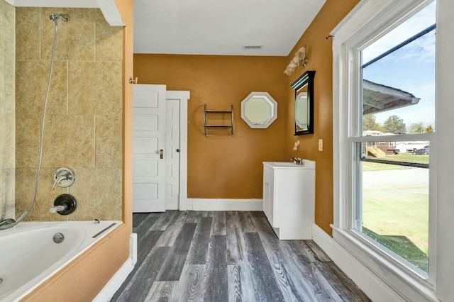 bathroom featuring tiled shower / bath, wood-type flooring, vanity, and plenty of natural light