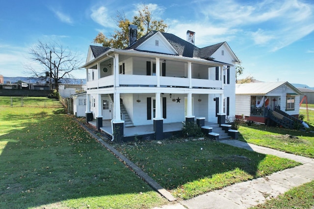 view of front facade featuring covered porch, a balcony, and a front lawn