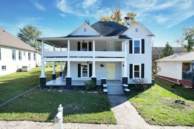 view of front facade with a porch, a balcony, and a front lawn