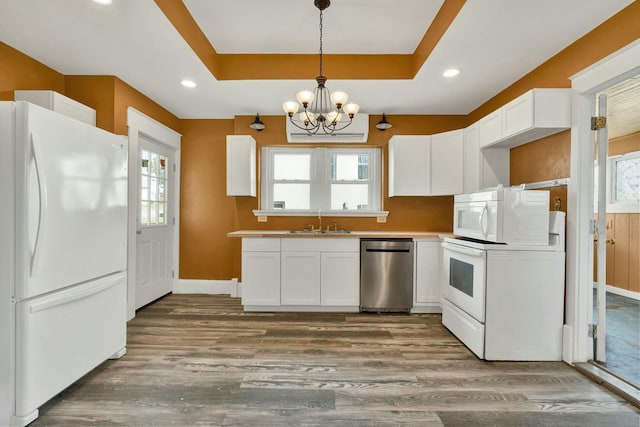 kitchen featuring white cabinetry, dark wood-type flooring, an inviting chandelier, a raised ceiling, and white appliances