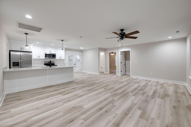 unfurnished living room featuring ceiling fan, french doors, light hardwood / wood-style floors, and sink