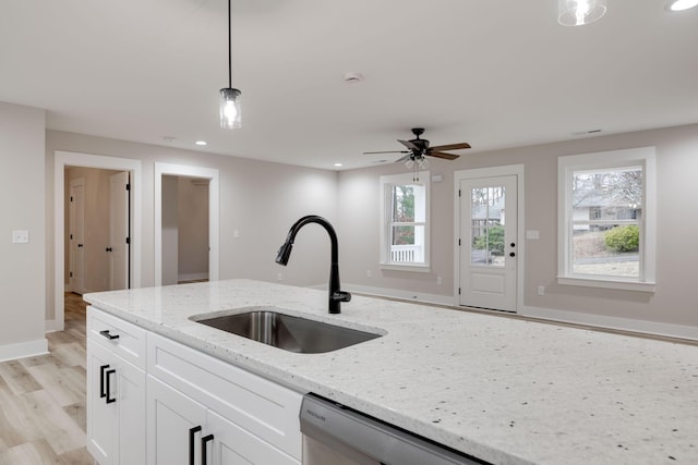 kitchen featuring light stone countertops, sink, ceiling fan, pendant lighting, and white cabinets