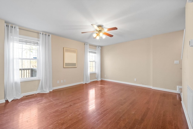 empty room with dark hardwood / wood-style flooring, plenty of natural light, and ceiling fan