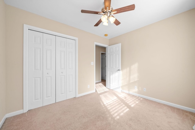 unfurnished bedroom featuring ceiling fan, light colored carpet, and a closet