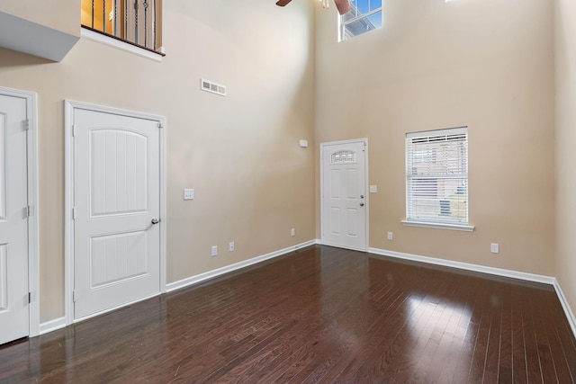 interior space with ceiling fan, dark wood-type flooring, and a high ceiling