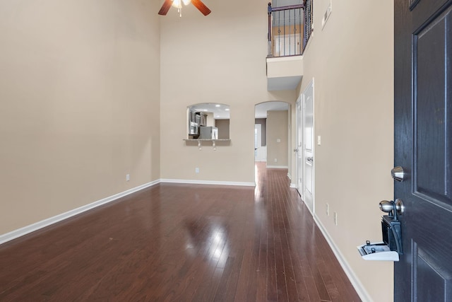 entrance foyer featuring ceiling fan, dark hardwood / wood-style flooring, and a towering ceiling