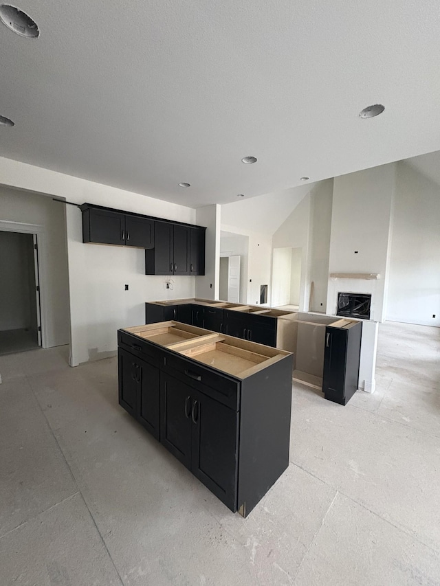 kitchen featuring dark cabinetry, cooktop, a fireplace, and a kitchen island