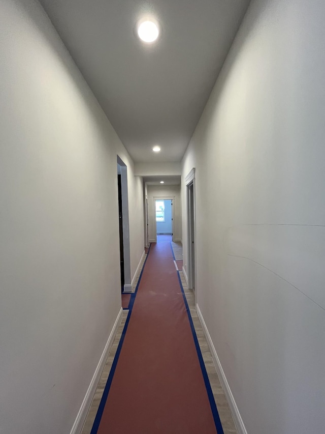 corridor with baseboards, wood finished floors, and recessed lighting