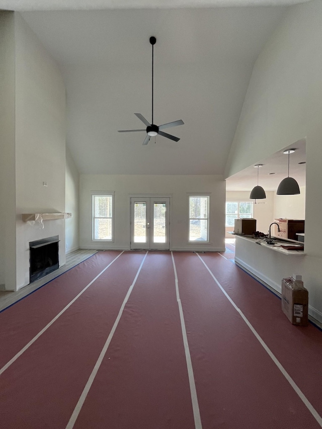 unfurnished living room featuring a healthy amount of sunlight, a fireplace, and high vaulted ceiling