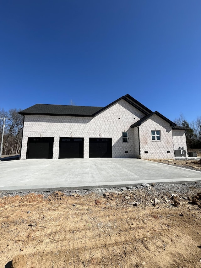 view of side of property featuring brick siding, driveway, and an attached garage