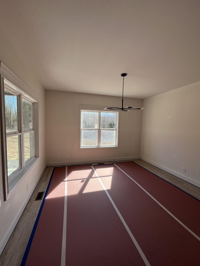 unfurnished room with wood finished floors, visible vents, and baseboards