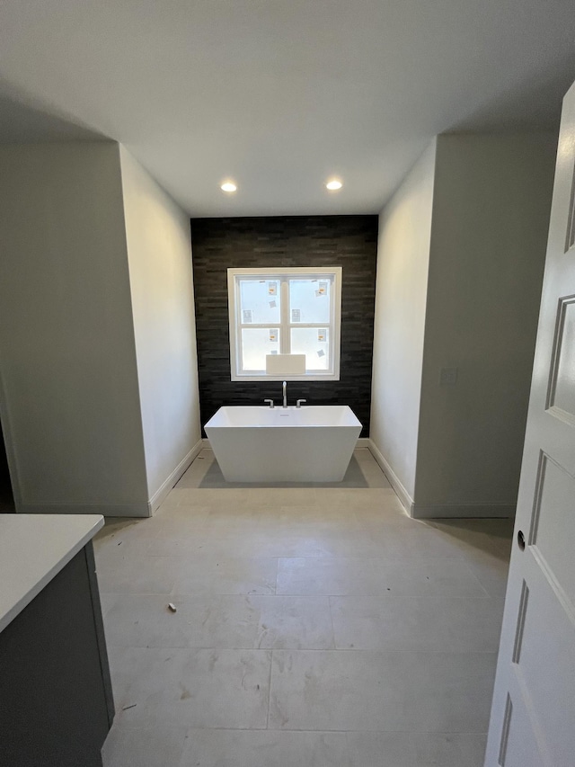 full bathroom featuring recessed lighting, an accent wall, vanity, a freestanding tub, and baseboards