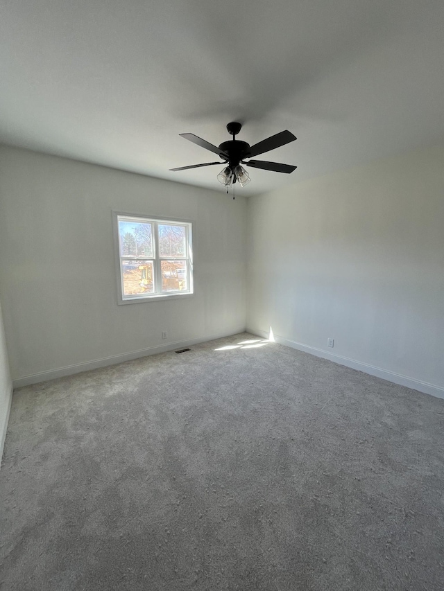 carpeted empty room featuring ceiling fan, visible vents, and baseboards