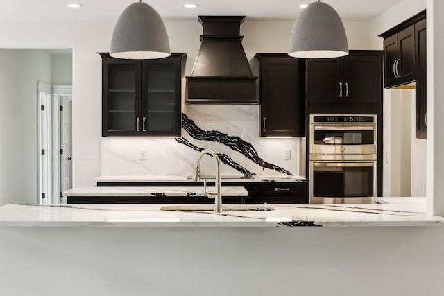 1049 Gholson Rd, Clarksville, TN 37043 - kitchen featuring stainless steel double oven, dark cabinetry, decorative light fixtures, light stone countertops, and tasteful backsplash