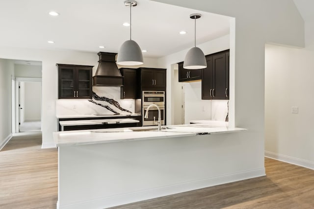 1049 Gholson Rd, Clarksville, TN 37043 - kitchen featuring premium range hood, light wood finished floors, baseboards, and a sink