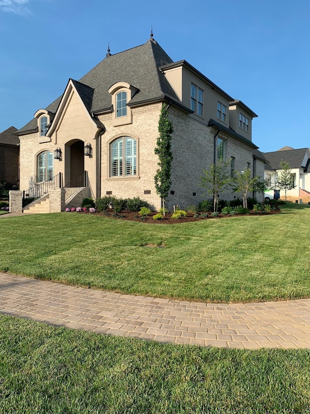 french country home featuring crawl space, brick siding, and a front lawn