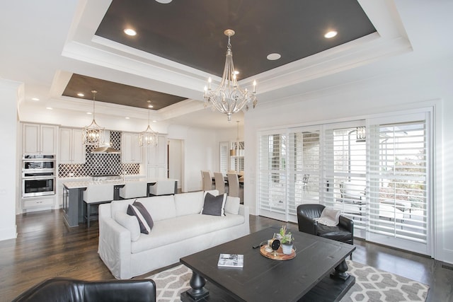 living area featuring a chandelier, a tray ceiling, dark wood-style floors, and crown molding