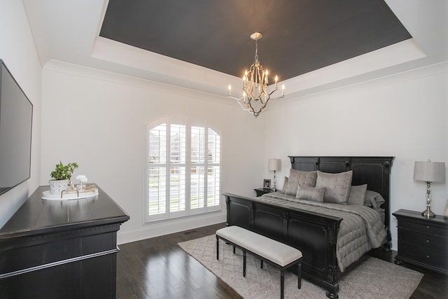 bedroom with dark wood-style floors, a tray ceiling, baseboards, and a notable chandelier