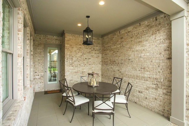 dining room with light tile patterned floors, brick wall, crown molding, and recessed lighting