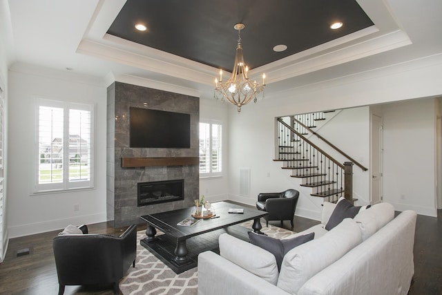 living room featuring baseboards, stairway, wood finished floors, a tray ceiling, and a fireplace