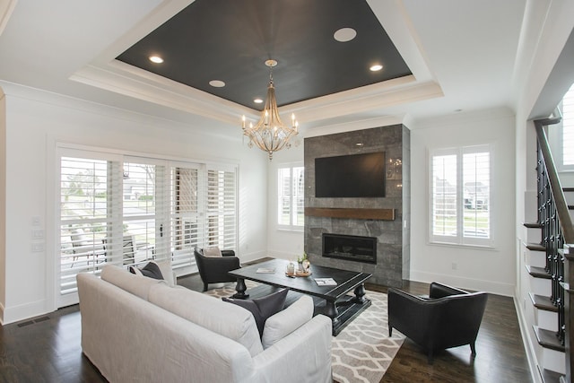 living area with a wealth of natural light, a raised ceiling, visible vents, and a large fireplace