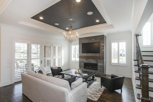 living room featuring dark wood finished floors, a fireplace, a raised ceiling, baseboards, and stairs