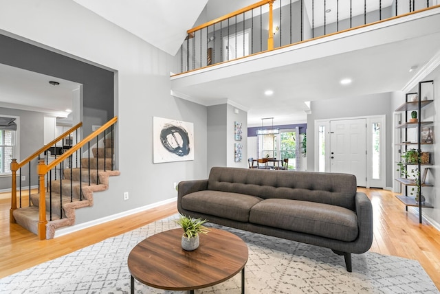 living room featuring hardwood / wood-style floors, high vaulted ceiling, and ornamental molding