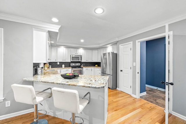 kitchen featuring light hardwood / wood-style floors, kitchen peninsula, and appliances with stainless steel finishes