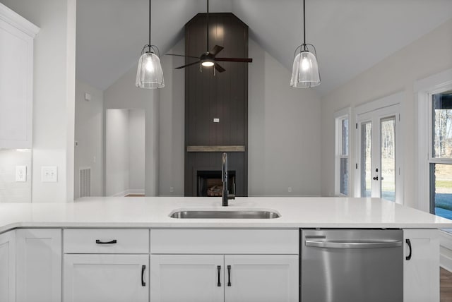 kitchen featuring white cabinetry, vaulted ceiling, stainless steel dishwasher, and sink