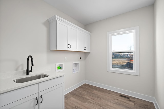 washroom with sink, cabinets, hookup for an electric dryer, hookup for a washing machine, and light wood-type flooring