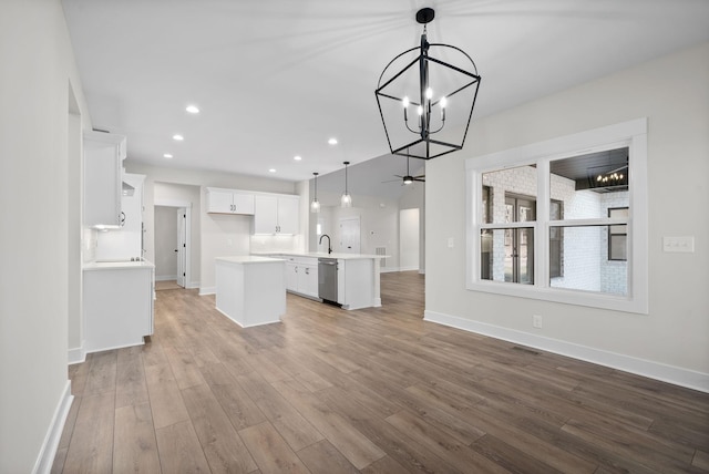 kitchen featuring dishwasher, hanging light fixtures, light wood-type flooring, a kitchen island, and white cabinetry