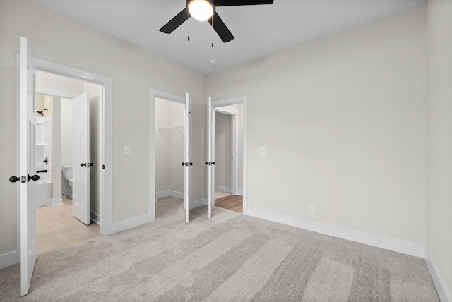 unfurnished bedroom with ceiling fan, a closet, light colored carpet, and a spacious closet