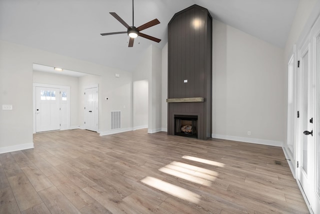 unfurnished living room featuring ceiling fan, a large fireplace, high vaulted ceiling, and light wood-type flooring