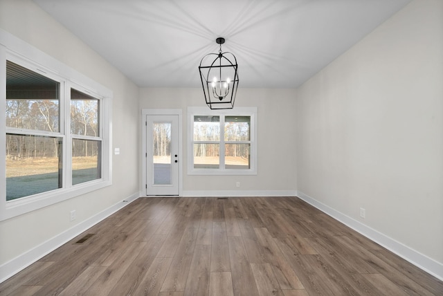 unfurnished dining area featuring a chandelier and hardwood / wood-style flooring