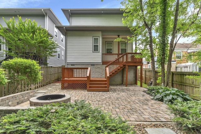 rear view of house with a wooden deck, a patio, and a fire pit