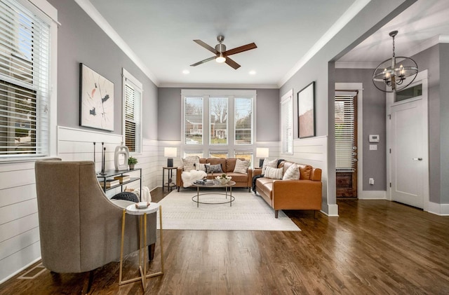 living room with crown molding, dark hardwood / wood-style flooring, and ceiling fan with notable chandelier