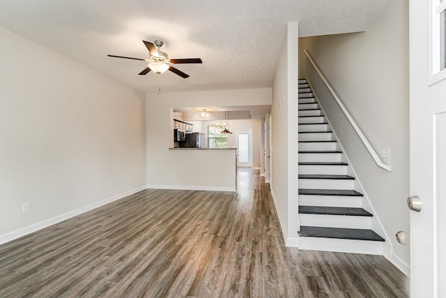 unfurnished living room with a textured ceiling, ceiling fan, and dark hardwood / wood-style floors